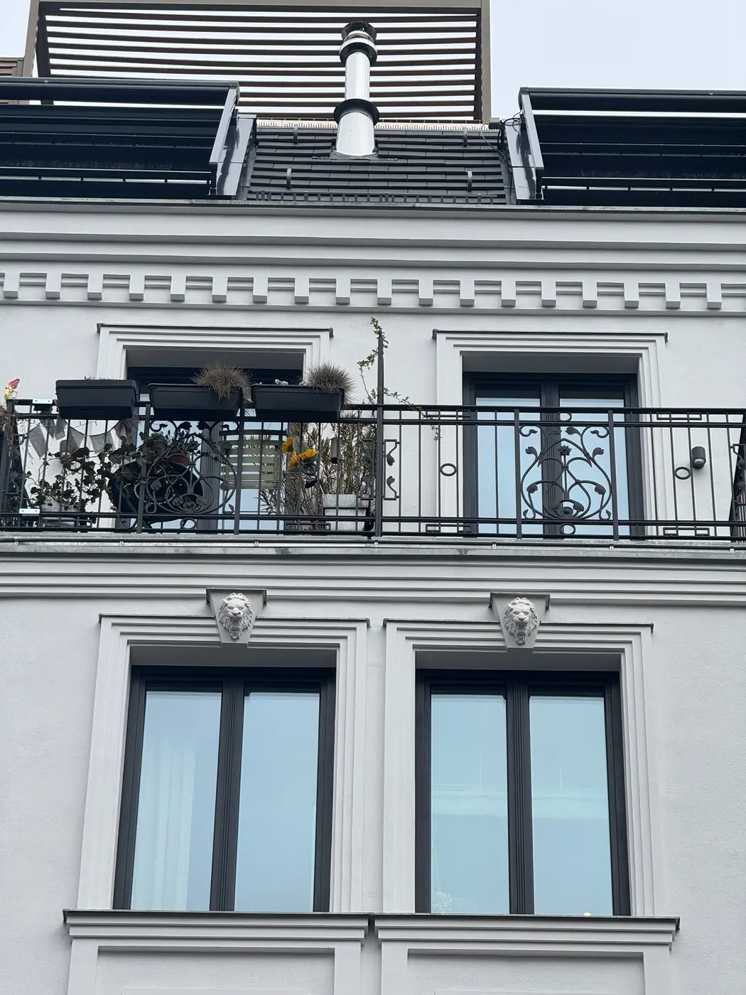 Fassadendetail mit Balkon, Zierband und dekorativen Löwenköpfen